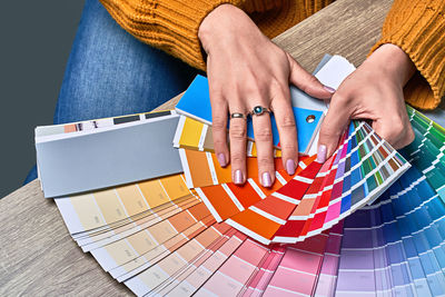High angle view of woman holding color swatch on table