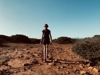 Girl walking along a rocky trail in winter sunlight