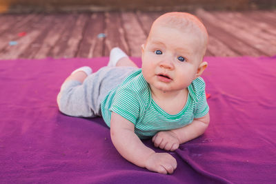 Portrait of cute baby girl lying on carpet