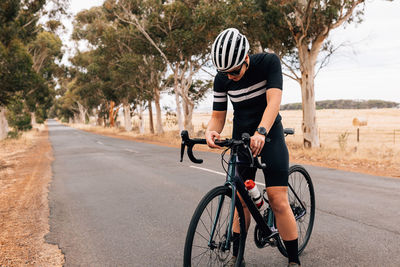 Woman standing on bicycle at road