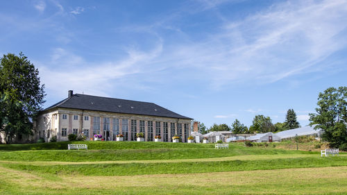 Houses on field by trees against sky