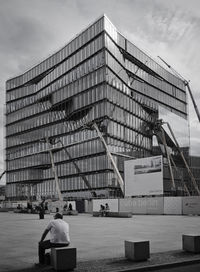 Rear view of people on modern building in city against sky