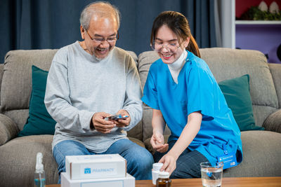 Portrait of smiling friends using laptop while sitting at home