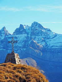 Cross shape on hill against snowcapped mountains