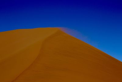 Scenic view of desert against clear blue sky