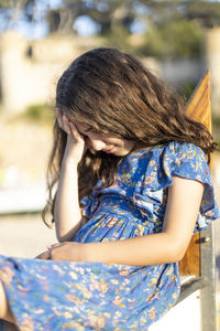 Girl with head in hand sitting on wood