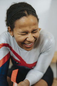 Teenage female athlete laughing while sitting in locker room