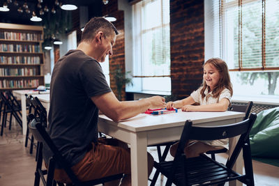 Father playing board game with her daughter in public library. child spending time with dad. play