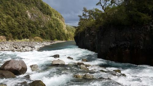 Scenic view of waterfall in forest against sky