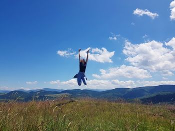 Man jumping on mountain against sky