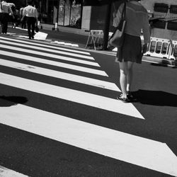 Low section of woman crossing road