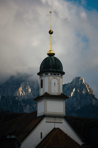 Moody view of cathedral tower with bavarian alps in the background.