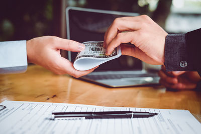 Cropped image of man holding mobile phone on table