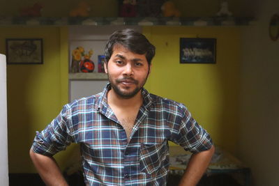 Portrait of young man standing against wall