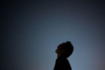 Low angle view of man with head back standing against sky at night