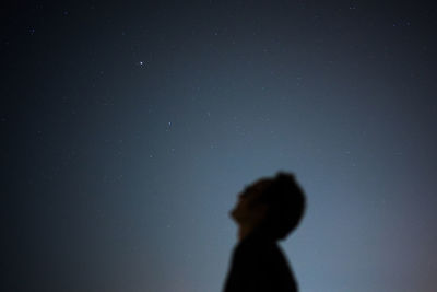 Silhouette woman standing against sky at night