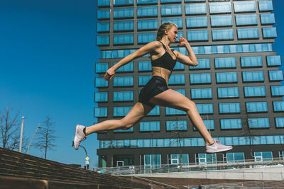 Low angle view of woman jumping against built structure