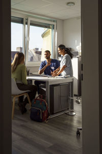 Male and female medical professionals talking with patient in doctor's office at hospital