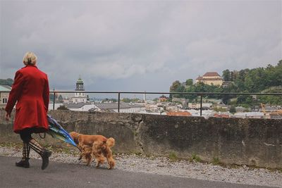 Rear view of man with dog standing in background