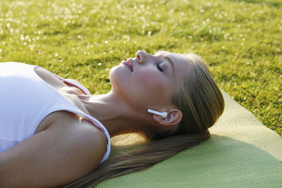 Woman with eyes closed lying on exercise mat