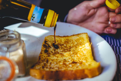 Cropped image of woman pouring sauce on bread