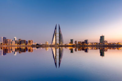 Reflection of illuminated buildings in river against sky