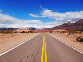 Road leading towards mountains against sky