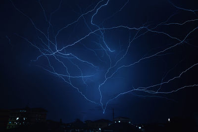 Low angle view of lightning over illuminated building at night