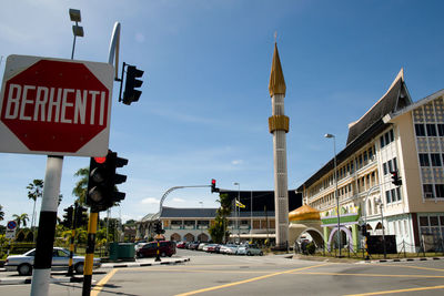 Road sign by street against buildings in city