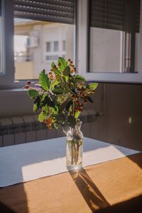 Flower vase on table by window