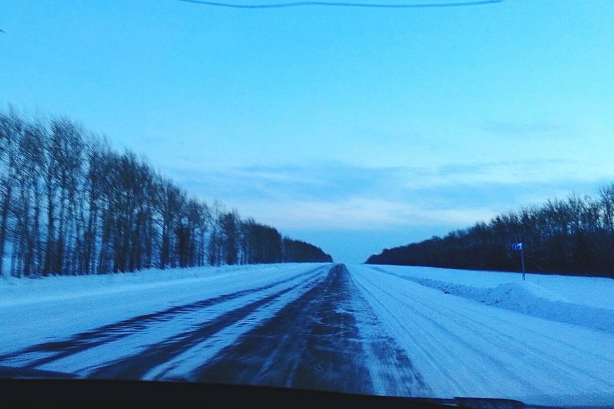 transportation, the way forward, road, diminishing perspective, vanishing point, snow, winter, tree, sky, cold temperature, road marking, blue, country road, nature, tranquil scene, windshield, tranquility, weather, beauty in nature, landscape