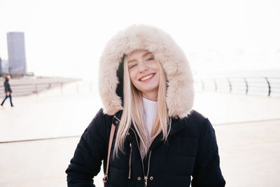 Happy smiling blonde girl in a fluffy hood on a white background. portrait. high quality photo