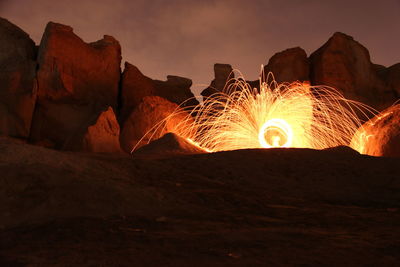 Illuminated wire wool in desert against rock formations at night