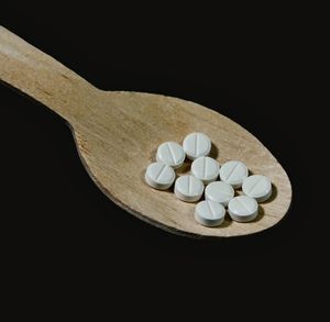 Medicines in wooden spoon over black background