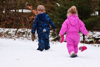 Rear view of girl walking on snow covered landscape