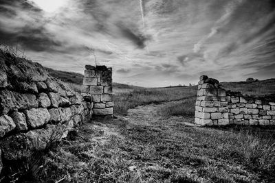 Stone wall on field against sky