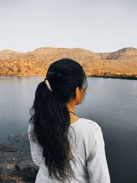 Rear view of man looking at lake against mountain