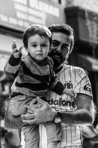 Portrait of father carrying son outdoors