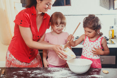 Cute girls preparing batter of cookies at home