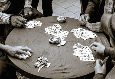 Cropped image of people playing cards at table