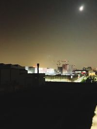 Silhouette factory against sky at night