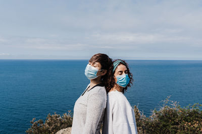 Lesbian couple standing by sea against sky