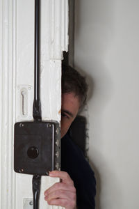 Portrait of burglar hiding behind door