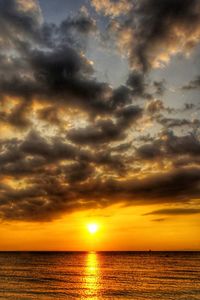 Scenic view of sea against dramatic sky during sunset