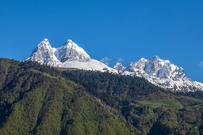 Scenic view of snowcapped mountains against clear blue sky