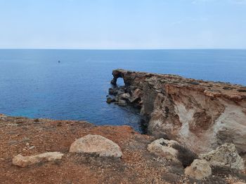 Rock formations on shore against sky