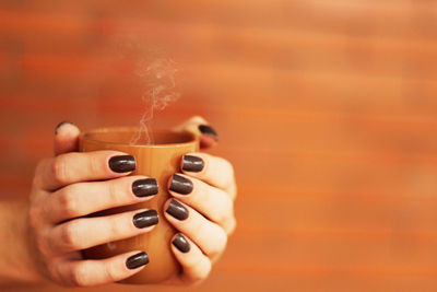 Cropped image of hands holding coffee cup 