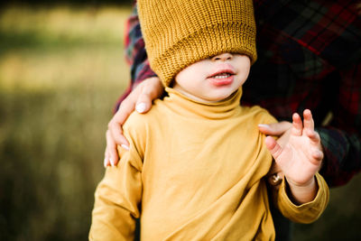 Boy standing with yellow hat on his head outdoor.