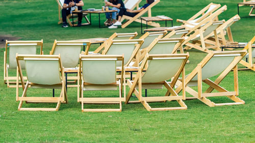 Many white deck chairs with tables for dinner in lawn is surrounded by shady green grass 