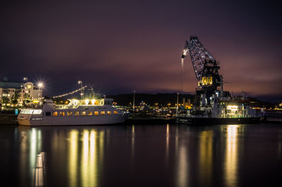 Illuminated ship moored at harbor against sky at night